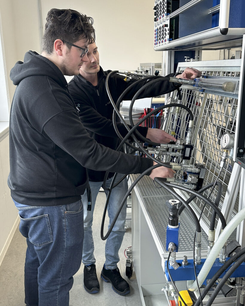Ausbildung für Steuerungstechnik: Zwei Teilnehmer arbeiten an einem hydraulischen Steuerungssystem, Kompetenzcampus Technik und Wirtschaft Bergisches Land, Remscheid